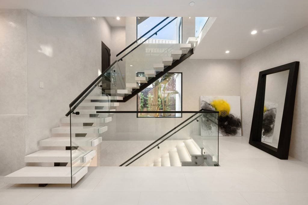 modern home interior featuring a set of stairs with white carpeting and glass railings